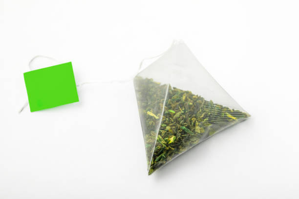 istock Tea Time. Pyramidal green tea bag with green label on white background 1885989797