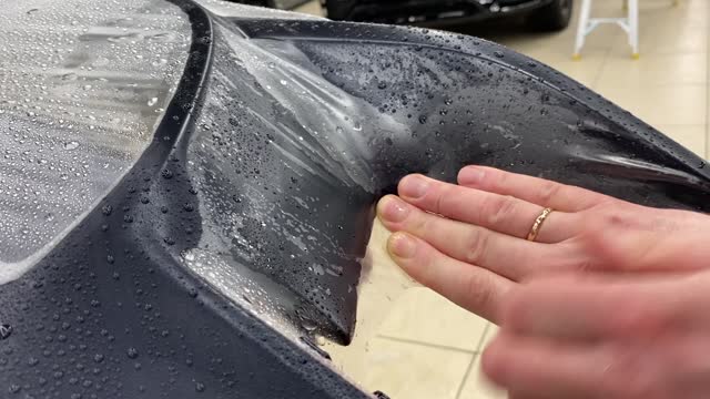 A car wrapping specialist applies a polyurethane film to the car. PPF protective film against chips and scratches. Car wrapping. Selective focus.