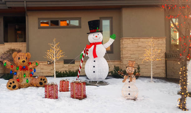 Snowman,Gifts Teddy Bear and trees light up the residential front yard at Christmas.