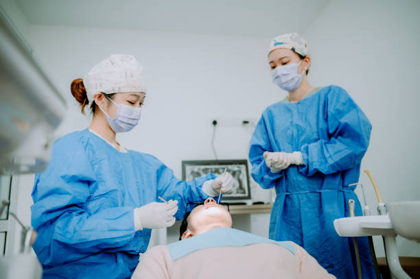 istock Asian Chinese dentist is cleaning patient teeth. 1886087643