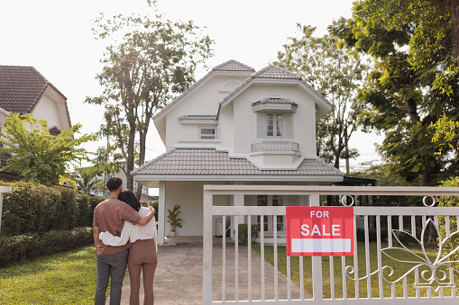 Couple stands embraced in front of the house, admiring their new home.