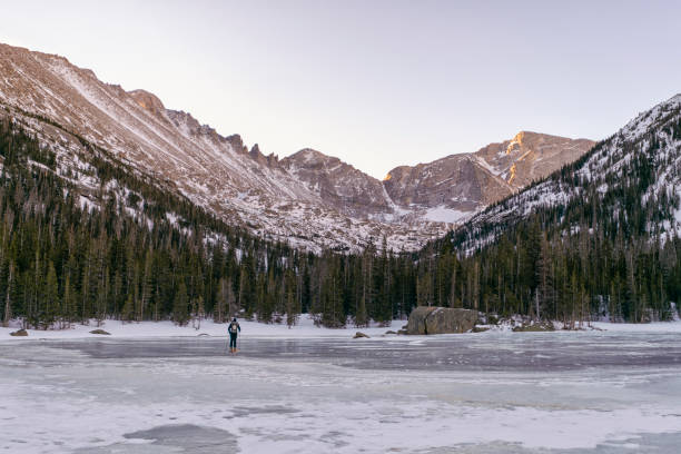 Skier travels over a frozen lake, Colorado Skier travels over a frozen lake, Colorado in Estes Park, Colorado, United States colorado rocky mountain national park lake mountain stock pictures, royalty-free photos & images