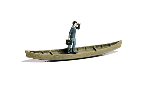 Miniature tiny people toy figure photography. Business opportunity concept illustration. Businessman using binocular telescope sail with boat. Isolated on a white background. Image photo
