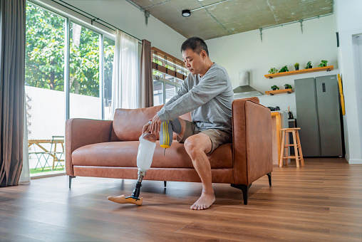amputated man sitting on sofa applying prosthetic leg