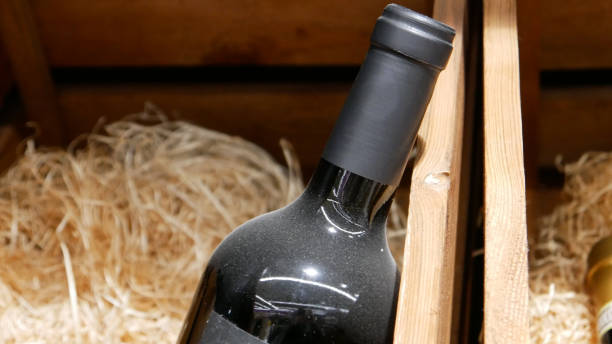 close-up of a dusty bottle of aged wine in a wooden box - dust old cabernet sauvignon grape aging process imagens e fotografias de stock