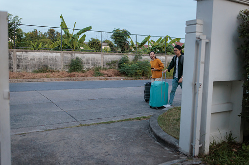 A young couple pulls their suitcases, heading towards their vacation house.