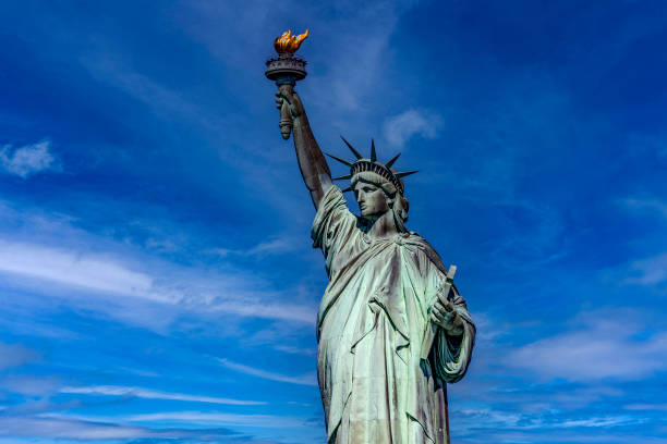 new york, vereinigte staaten von amerika; 1. juni 2023: panoramafoto der freiheitsstatue mit ihrer fackel unter einem schönen sonnigen tag und blauem himmel. - statue apple roman sculpture stock-fotos und bilder