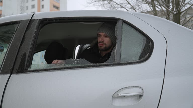 Man knocks out and breaks with his fist ice crust instead of side window of car.