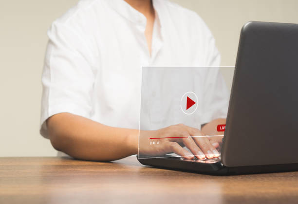 istock Man watches a live stream on a virtual screen with a laptop while sitting at the table. 1886504949