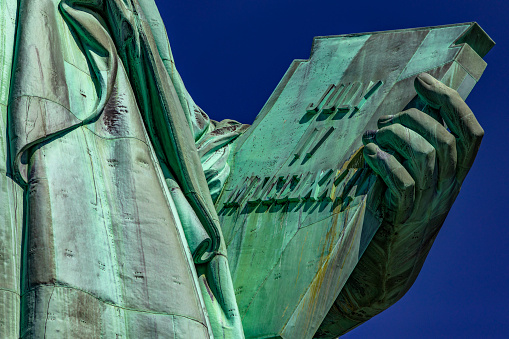 Photo of the hand of the Statue of Liberty holding the book of the American Declaration of Independence that reads: July 4, 1776 in Roman numerals.