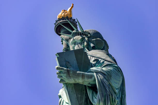 die new yorker freiheitsstatue im profil, unter einem sonnigen tag im big apple mit dem blauen himmel von new york in den vereinigten staaten von amerika. - statue apple roman sculpture stock-fotos und bilder