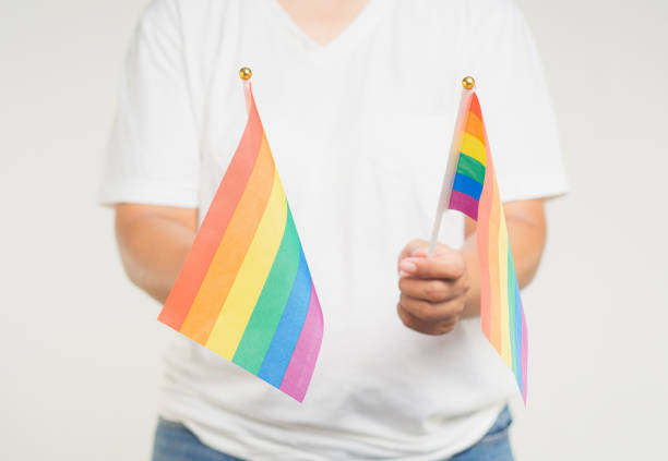 istock Close-up of a hands holding a rainbow flags while standing on a gray background. 1886510582