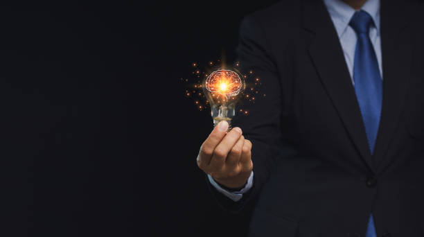 istock Close-up of hand a businessman holding a lighting bulb with lighting while standing on a black background 1886511088