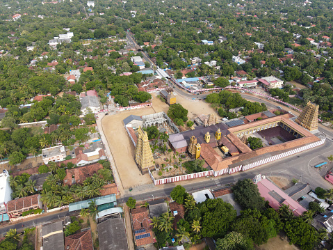 The aerial photographs capture the grandeur of the Nallur Kandaswamy Temple, a historically and architecturally significant Hindu temple located in Jaffna, Sri Lanka. The temple's majestic gopurams rise into the sky, intricately adorned with Hindu deities, painted in vibrant hues that resonate with the spirituality of the place. These images reveal the temple's expansive courtyard, traditional Dravidian architecture, and the surrounding town's layout. The temple complex is a focal point in the area, surrounded by the verdant foliage of the tropics and the bustling life of Jaffna. The golden sunlight bathes the temple, highlighting its importance as a center for worship and community gathering