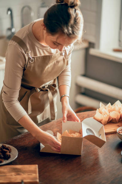 istock female bakery owner packs boxes for customer's order in birthday, Birthday package. small business entrepreneur and concept of food delivery 1886555800