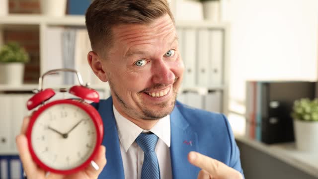 Portrait of smiling manager holding red alarm clock for ten in morning 4k movie