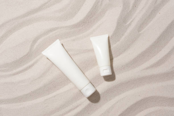 istock Close-up of two unlabeled cosmetic tubes placed on a sandy background with wave patterns. Mockup for cosmetics advertisement with blank label. 1886611407