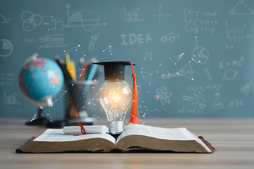 Graduation cap with a lightbulb on the book and globe in the classroom. Education learning concepts in school or university. Idea knowledge of innovative technology, science, and mathematics.