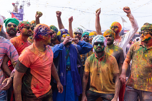 Anandpur Sahib, Punjab, India - March 2022: Group of sikh people (nihang sardar) during the celebration of hola mohalla at anandpur sahib with coloured faces during holi festival. Selective focus on colorful face.
