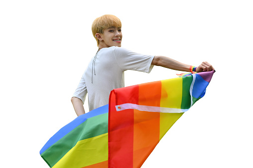 Portrait with LGBT Asian teenage boy flicking the rainbow flag, isolated on the white background.
