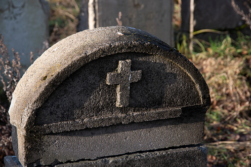 Old and worn tombstone with a Catholic cross.