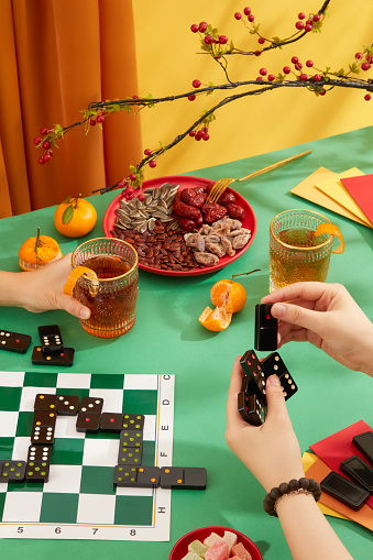 Two people were playing dominoes on the table, surrounded by a plate of dried nuts and jam, tangerines, two glasses of carbonated water and red envelopes. The Tet atmosphere is bustling.