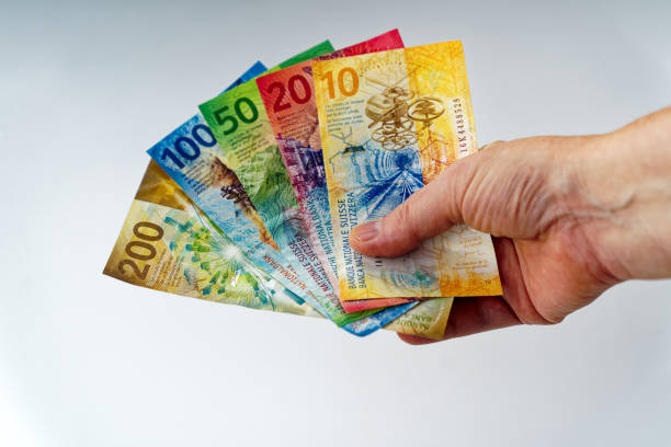 bunte schweizer banknoten fächerförmig von der hand einer frau gehalten. - swiss currency switzerland currency paper currency stock-fotos und bilder
