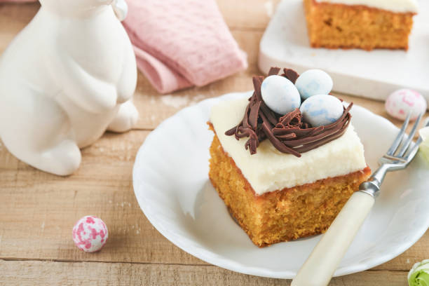 istock Easter carrot cake bars decorated with chocolate nest and chocolate candy eggs blossoming cherry or apple flowers on rustic light wooden backgrounds. Easter holiday meal. Traditional Easter food. 1886770825