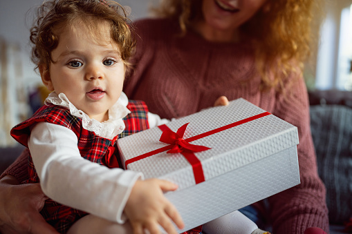 Portrait of an Caucasian baby girl holding an Christmas present