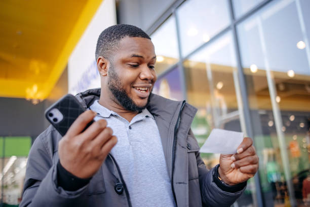 istock Young man finds out that he has winning ticket in hands. Surprised and happy face while walking outdoors. 1886845949