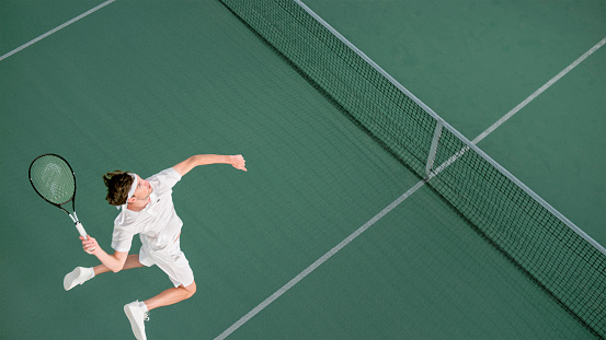 Overhead view of male tennis player playing match in tennis court.
