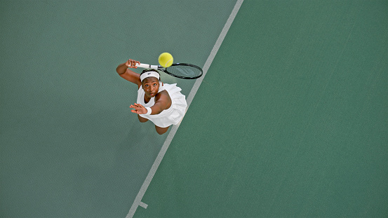 Overhead view of female tennis player playing match in tennis court.