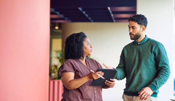 istock Manager and colleague talking in corridor at office breakout space 1886852724