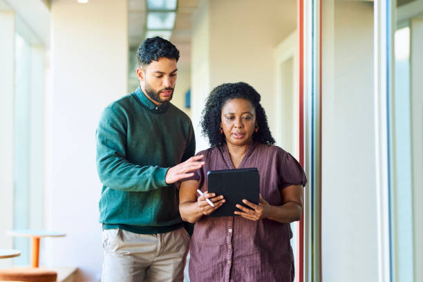 istock Manager and male colleague using digital tablet in corridor at office breakout space 1886852728