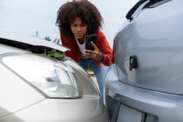 istock Half Thai African driver check for damage after a car accident before taking pictures and sending insurance. Online car accident insurance claim after submitting photos and evidence to an insurance. 1886853270