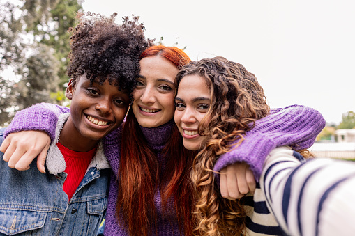 three girls take a selfie. group of young multicultural women taking a photo looking at camera