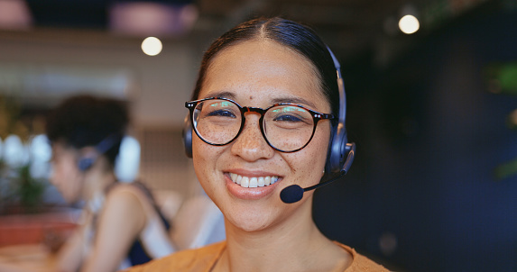 Consultant wearing eyeglasses and headset looking at camera with cheerful smile in call center