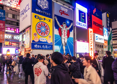 Osaka, Japan - Streets by the canal in Dōtonbori crowded on a Saturday night in March, with the bright billboards illuminating the area.