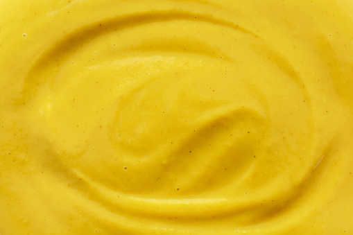 Yellow mustard sauce texture background. Cooking preparation concept.