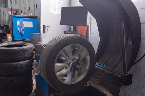 Computer wheel balancing on special equipment machine tool in auto repair service. Stand for balancing wheels of car. The wheel is blurred due to the fast rotation.