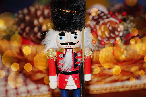 Nutcrackers on a glass table with out of focus christmas lights in the background.