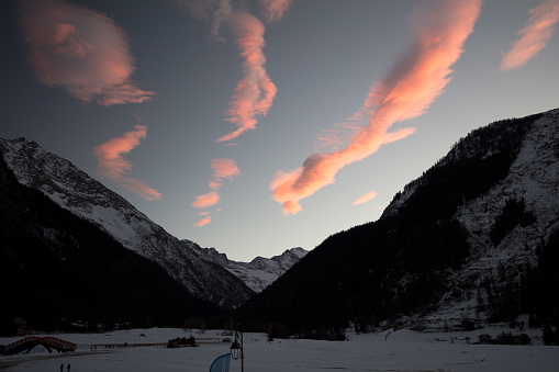 After sunset some clouds ignite the sky above the valley, Valnontey, at the head of which the Gran Paradiso massif stands