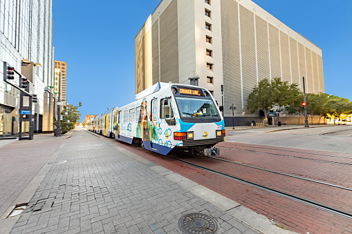 Dallas, USA - November 6, 2023: streetcar operating in downtown Dallas with advertising with happy young girl painted on wagon.