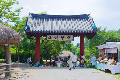 Andong City, South Korea - August 12th, 2023: The main entrance to Hahoe Folk Village, characterized by its traditional Korean gate, welcomes visitors beneath, offering a gateway to the historical and cultural richness within.