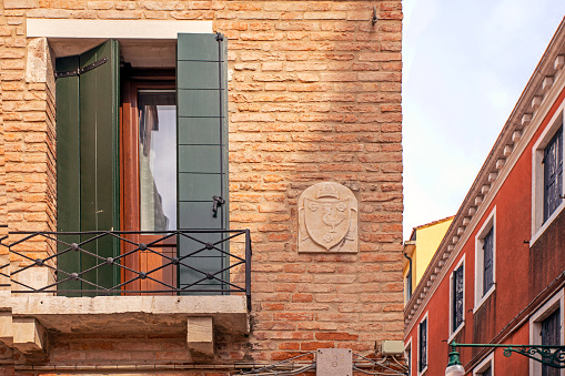 Venetian balcony window with green shutters on an ancient brick building