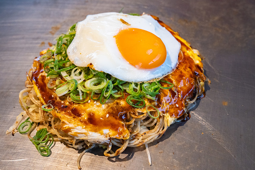 Hiroshima-style okonomiyaki in Hiroshima prefecture, Japan. Okonomiyaki is a Japanese-style pancake made from egg, flour and water with lots of toppings.