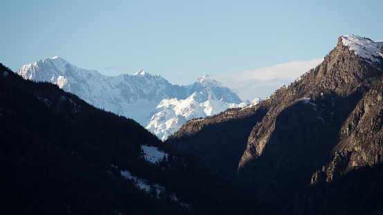 The mountain peaks surrounding the village stand out in the dim light of the late winter afternoon. In the background, the Mont Blanc massif.