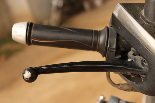 A closeup shot of a scooter or bike's Front break and accelerator in black and grey color