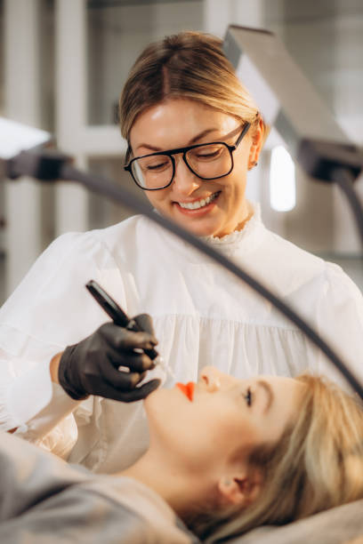 istock Professional permanent makeup artist and her client during lip blushing procedure 1887167690