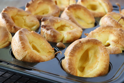 Stock photo showing close-up view of a tray of individual Yorkshire puddings cooked to be served with a roast dinner. These freshly baked Yorkshire puddings have risen especially well, due to preheating the tray and adding extra eggs to the batter.